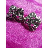 Запонки в форме цветов или абстрактных узлов из серебристого металла.